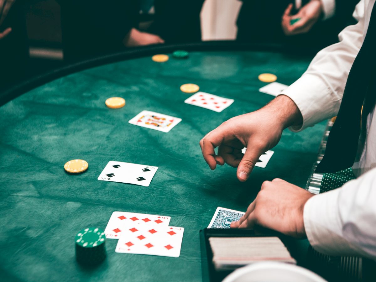 The image shows a casino scene with a dealer handling cards on a green table, surrounded by poker chips and players.
