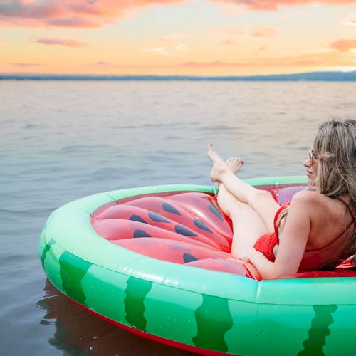 Two people relaxing on a colorful inner tube drifting on calm water at sunset, enjoying a peaceful, tropical moment.
